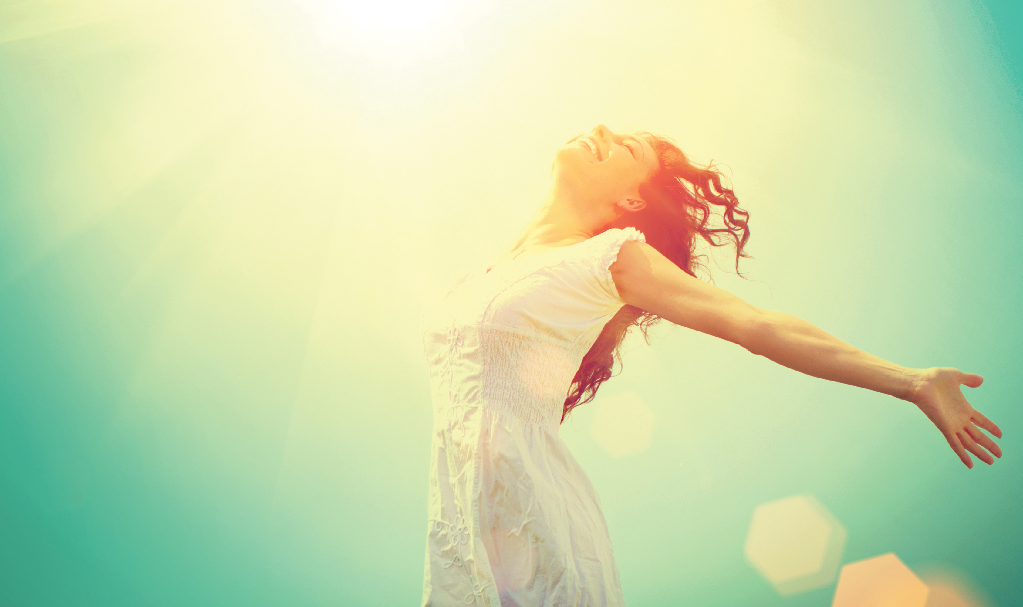 Femme souriante les bras ouverts en direction du soleil, bonheur et sérenitude